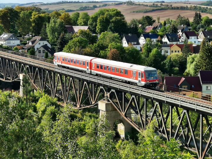 ein roteer Triebwagen der Baureihe 628 fährt über eine Eisenbahnbrücke