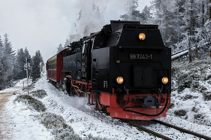Eine Dampflokomnotive fährt durch eine verschneite bergige Landschaft