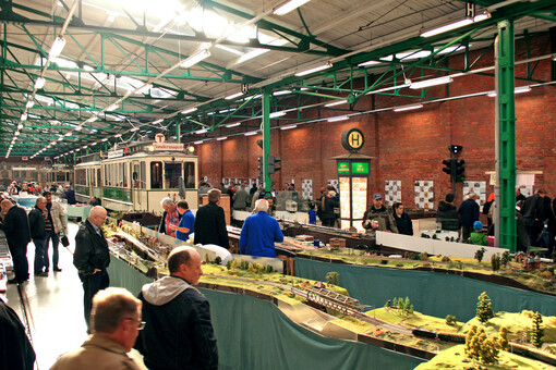 Menschen sehen sich eine Modelleisenbahn in der Wagenhalle des Museumsdepots Sudenburg an.