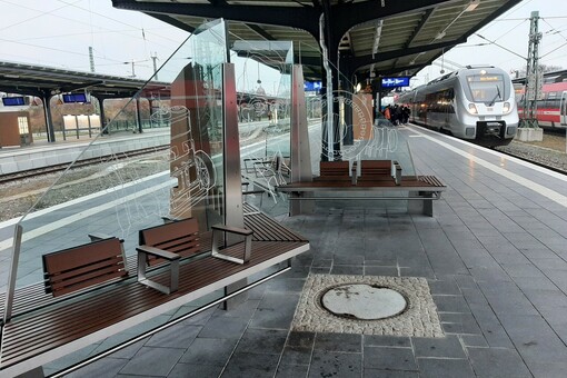 Neugestalteter Bahnsteig in Dessau Hauptbahnhof mit Sitzänken aus Holz und verzierten Glaswänden.